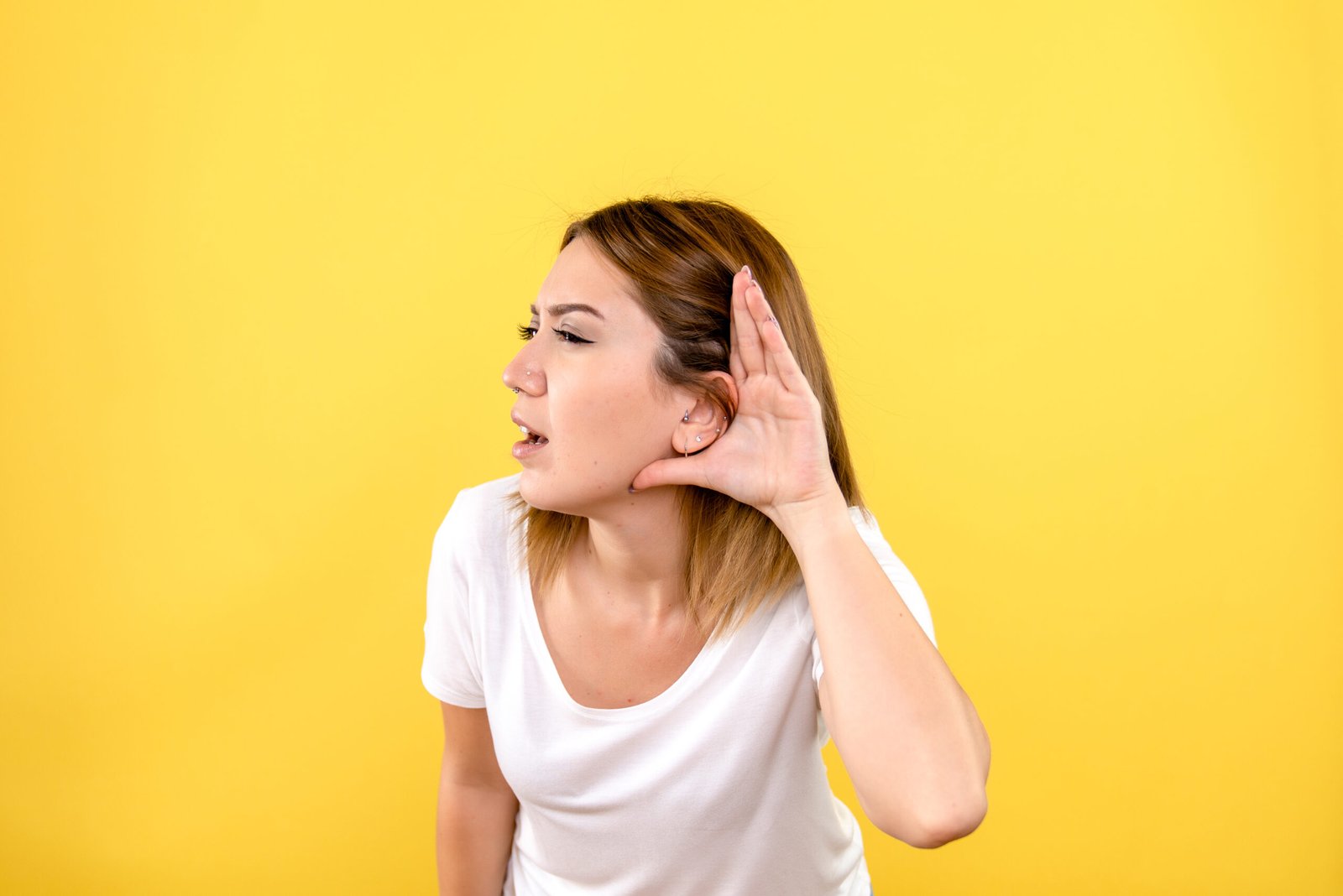 Vista frontal, de, mujer joven, escuchar, en, pared amarilla