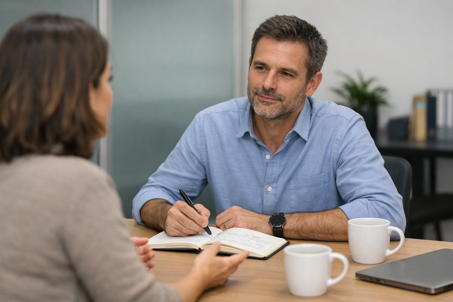 Psicólogo de Recursos Humanos conversando com uma funcionária em uma reunião individual sobre comunicação e trabalho no escritório.